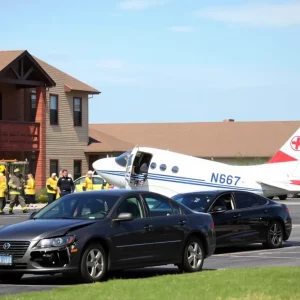 Scene of a small plane crash in a retirement community parking lot with emergency services responding.